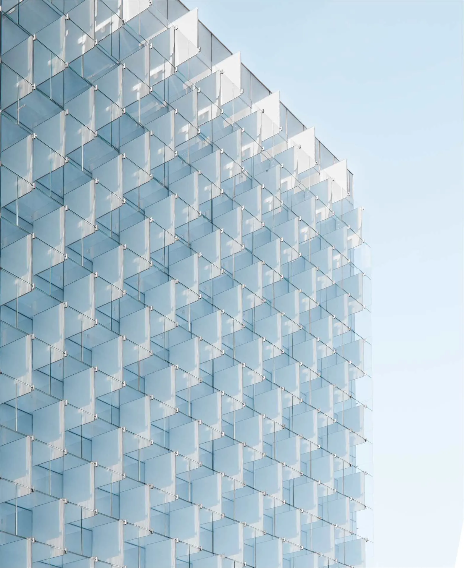 corner of glass building reflecting the blue sky