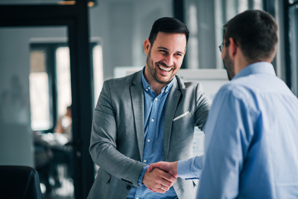 Two professionals shaking hands in a formal office setting, symbolizing a successful business deal