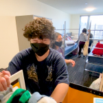 Student unpacking belongings in dorm room.