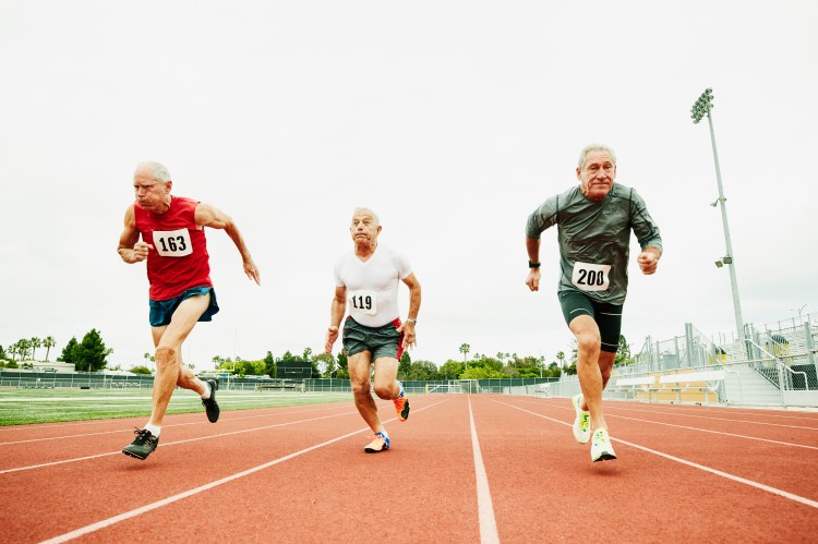 Three senior men sprinting in a track race.